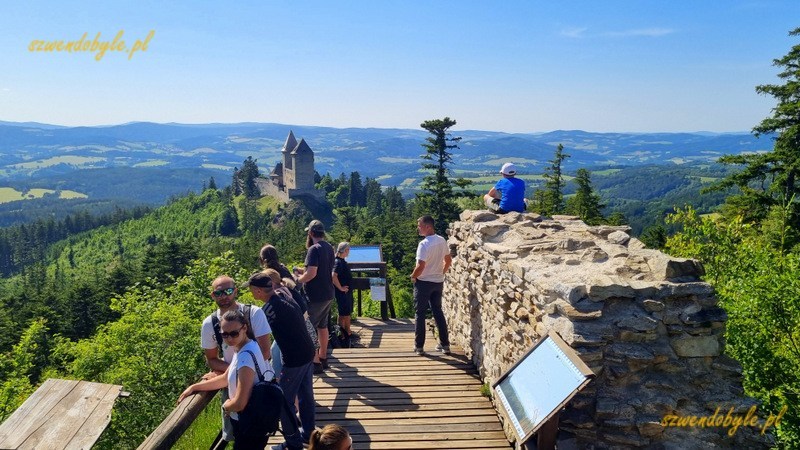 Czechy, Szumawa. Taras widokowy Pustý Hrádek z widokiem na zamek Kašperk. Na tarasie stoi kilka osób. 20250621_161338-ink