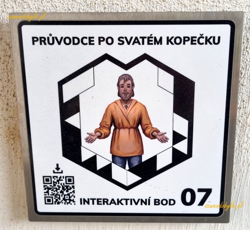 Ołomuniec, Svatý Kopeček. Tabliczka z kodem QR. Pośrodku postać przewodnika-pielgrzyma. 