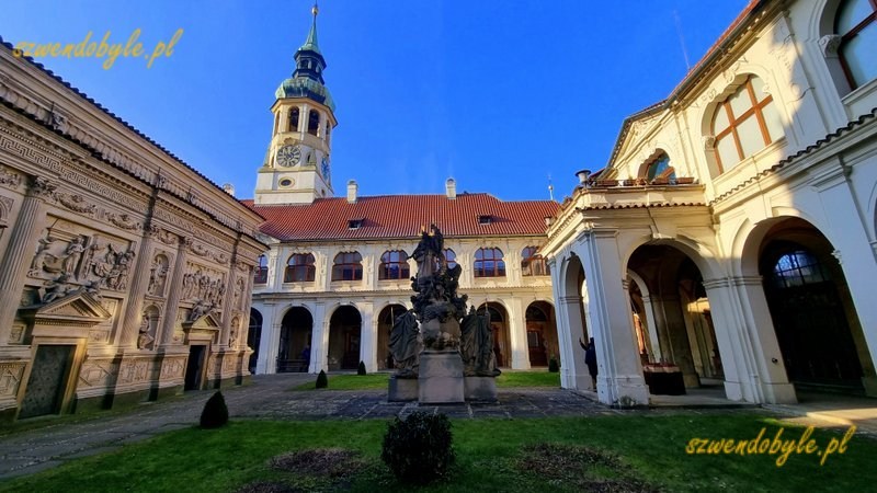 Praga, Loreta czyli kompleks pielgrzymkowy epoki baroku. Widok z lewej strony dziedzińca - po lewej domek loretański. Po prawej i naprzeciw arkady, a ponad nimi wieża wieża z zegarem. 20251226_105310-ink