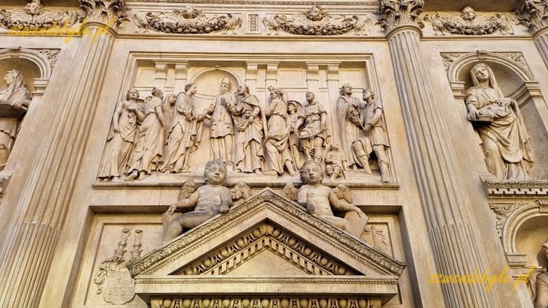 Praga, Loreta czyli kompleks pielgrzymkowy epoki baroku. Dziedziniec, domek loretański. Zbliżenie na tympanon z figurkami 2 anioł&oacute;w. Powyżej płaskorzeźba. 20251226_105706-ink