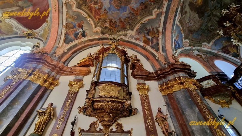 Praga, Loreta czyli kompleks pielgrzymkowy epoki baroku. Wnętrze kościoła Narodzenia Pańskiego. Na ścianie ozdobny barokowy przeszklony balkon wewnętrzny. 20251226_110251-ink