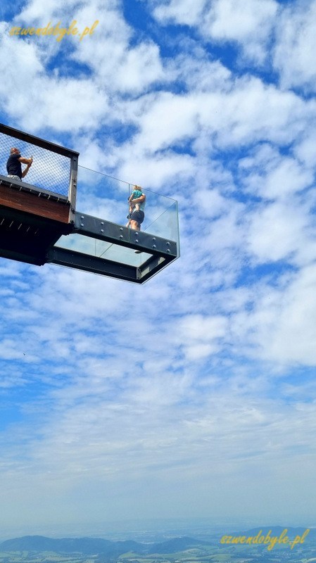 Czechy, Beskid Morawsko-Śląski,Stezka Vala&scaron;ka. Widok z dołu na szklany balkon na końcu ścieżki w koronach drzew na tle nieba.. 20250809_133324-ink