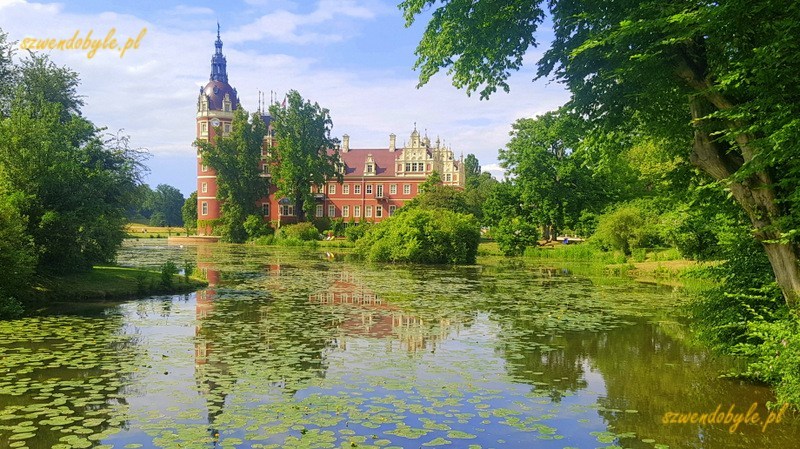 Bad Muskau, Neues Schloss / Mużaków. Nowy Zamek. Widok na zamek odbijający się w wodzie. Na powierzchni stawu pływają liście roślin wodnych. 20230614_161619-ink