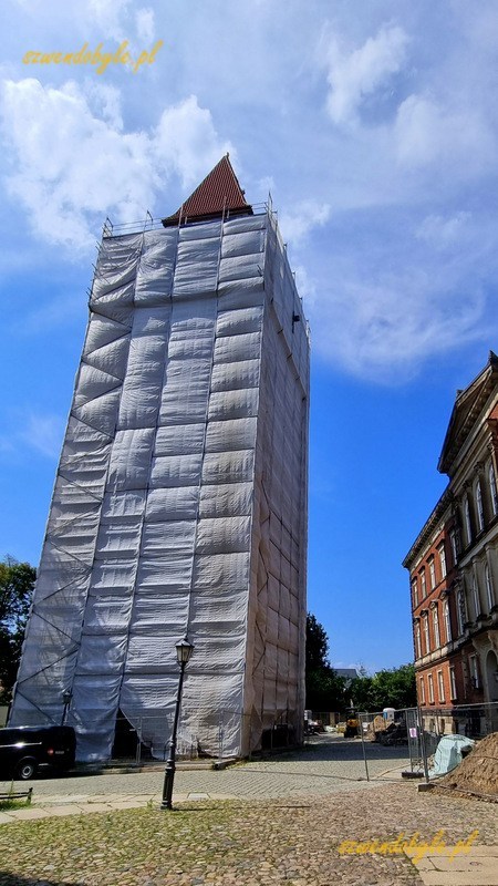 Cottbus, wieża zamkowa (Schlossturm). Na zdjęciu wieża szczelnie zasłonięta podczas remontu, widać jedynie fragment dachu. 20240626_152814-ink