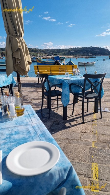 Malta, stoliki restauracji na brzegu w porcie w Marsaxlokk.