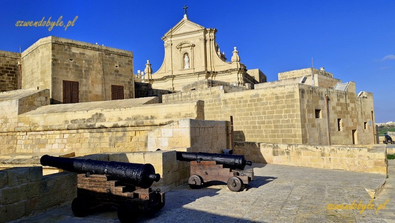 Gozo, Rabat (Victoria) - armaty na terenie cytadeli. Powyżej budynków widać fragment fasady katedry. 20250303_161420-ink