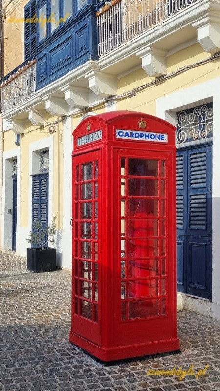 Malta, Marsaxlokk. Angielska budka telefoniczna na tle budynku. 