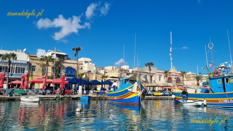 Malta, Marsaxlokk. Widok z wody na miasteczko i port. 