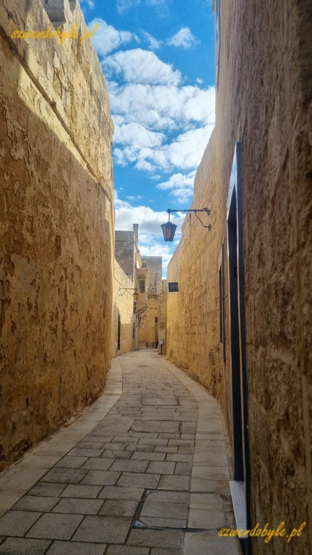 Mdina, wąska kamienna uliczka pomiędzy kamiennymi ścianami.