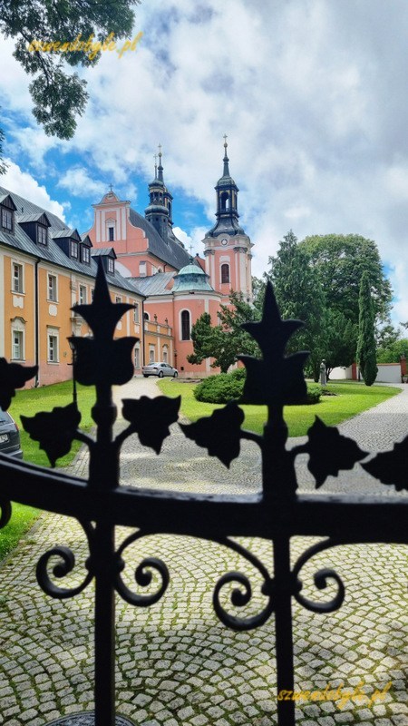 Lubuskie. Gościkowo-Paradyż, widok na budynek klasztoru cystersów i kościół św.Marcina zza ogrodzenia. Na pierwszym planie fragment kutego, ozdobnego ogrodzenia. 20240622_133357-ink