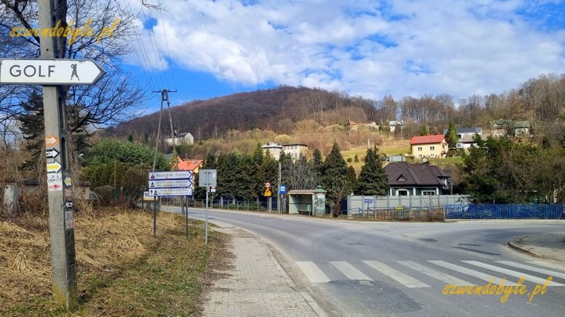 Małopolska, Krzeszowice, ż&oacute;łty szlak w kierunku klasztoru w Czernej. Po lewej na betonowym słupie wyraźne strzałki wskazujące zmianę kierunku szlak&oacute;w w prawo. Jest także tabliczka skrętu z napisem"GOLF". 20260315_114654-ink