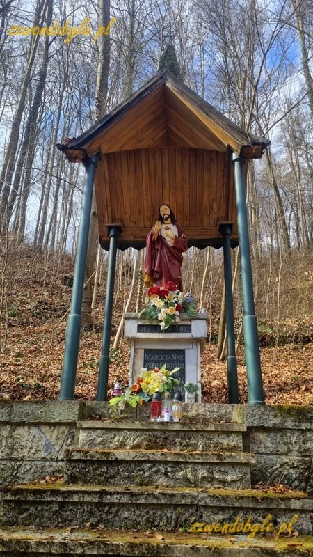 Małopolska, szlak Krzeszowice - Czerna. Kapliczka (drewniany dach wsparty na 4 metalowych słupkach) z figurą Jezusa. Pod figurą kwiaty i znicze. 20260315_120432-ink