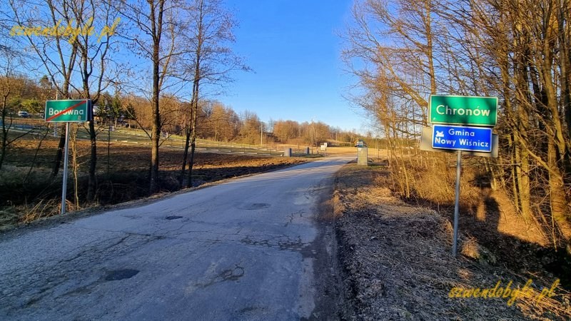 Małopolska,rezerwat Skałki Chronowskie. Asfaltowa droga, po prawej znak drogowy informujący o początku wsi Chron&oacute;w. Po lewej znak drogowy informujący końcu wsi Bor&oacute;wna. 20260307_163205-ink