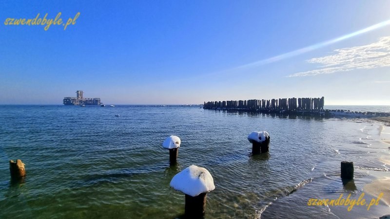 Gdynia, Babie Doły. Widok na pale wbite w dno morza. Pośrodku zdjęcia torpedownia. Na pojedynczych palach śnieżne czapy. 20260228_091840-ink