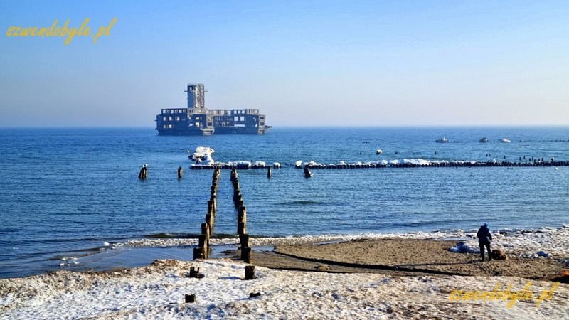 Gdynia, Babie Doły. Widok na pale wbite w dno morza. Pośrodku zdjęcia torpedownia. Na pierwszym planie śnieg na plaży. 20260228_093605-ink