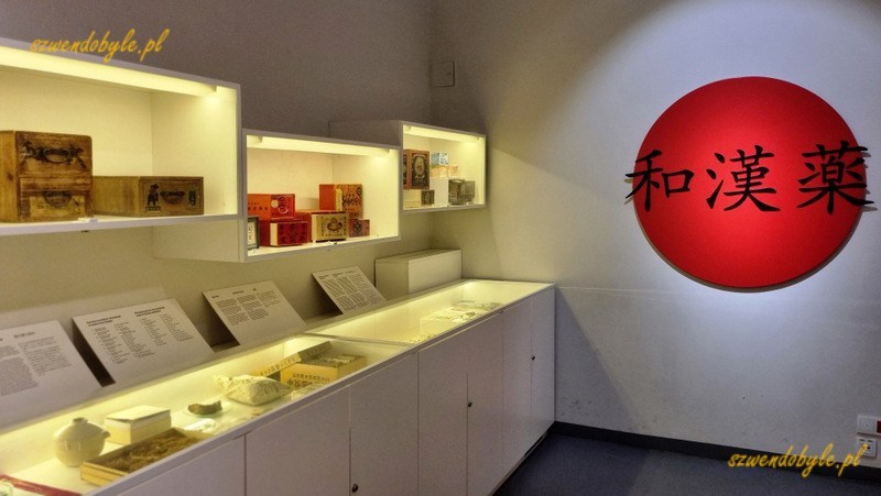 Warszawa, Muzeum Farmacji. Regał z ekspozycją japońską. Na ścianie obok czerwone koło - symbol Japonii.