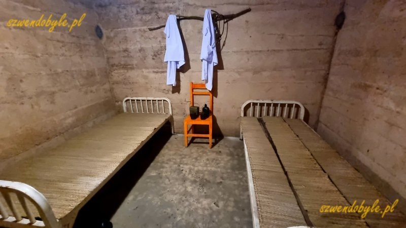 Wietnam, wyspa Cát Bà, jaskinia, w której mieścił się szpital wojskowy, czyli Military Hospital Cave. Niewieki pokój mieszkalny - betonowe ściany, 2 łóżka,1 krzesło i białe kitle wiszące na gałęzi. 20251124_115739-ink