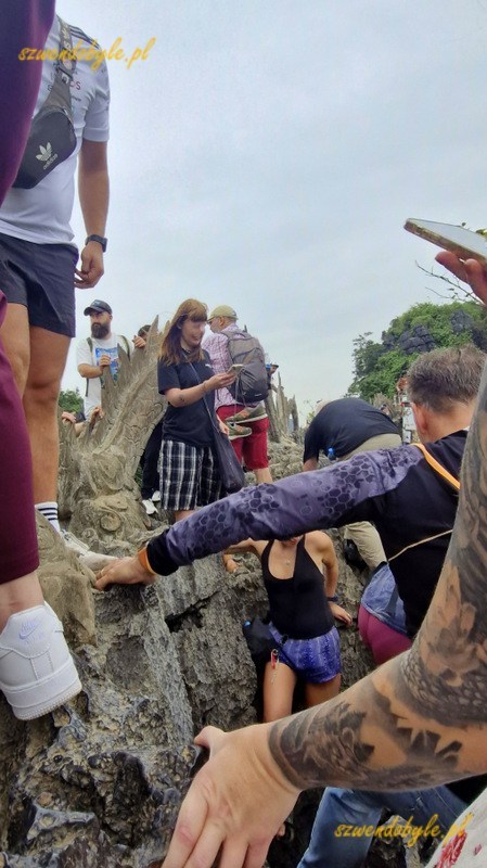 Wietnam, region Ninh Binh. Tłum ludzi mozolnie jeden za drugim idzie po ostrych kamieniach wzdłuż figury smoka na szczycie g&oacute;ry. 20251111_112139-ink
