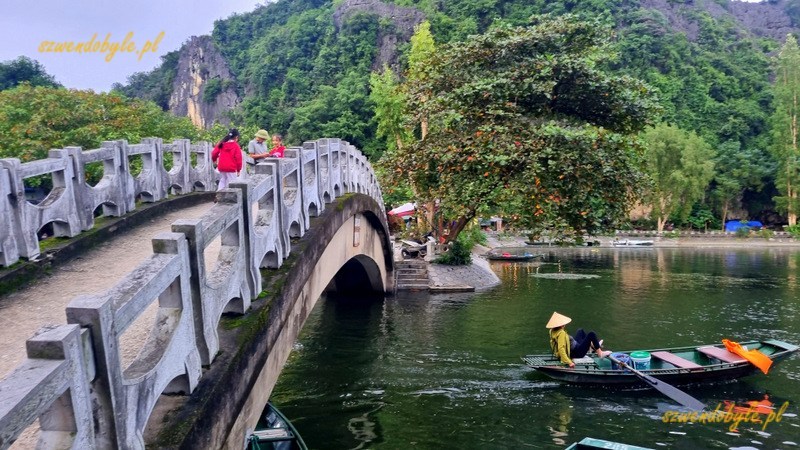 Tam Coc, Vietnam. Łukowaty most kamienny nad rzeką Ngo Dong na terenie miasteczka. Jedna ł&oacute;dź przepłynęła już pod mostem. 20251110_165833-ink