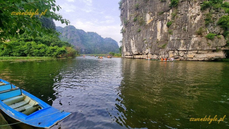 Tam Coc, Vietnam. Widok na rzekę Ngo Dong z przystani w rejonie świątyń. Po lewej, na pierwszym planie pojedyncza niebieska ł&oacute;dź. 20251111_152020-ink
